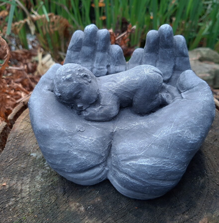 Handen dragen een baby beeldje, teder en lief beeld uit steen in grijs, mooi voor binnen of buiten, winterhard / LAATSTE