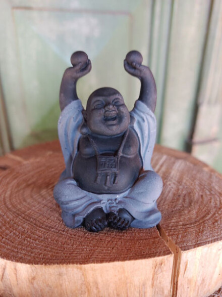 Happy Boeddha met parels in de lucht en zijn mantel voor bescherming uit steen met hematiet edelsteen